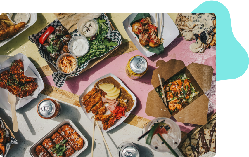 A birds eye view of a table filled with food in to go dishes and drink cans.